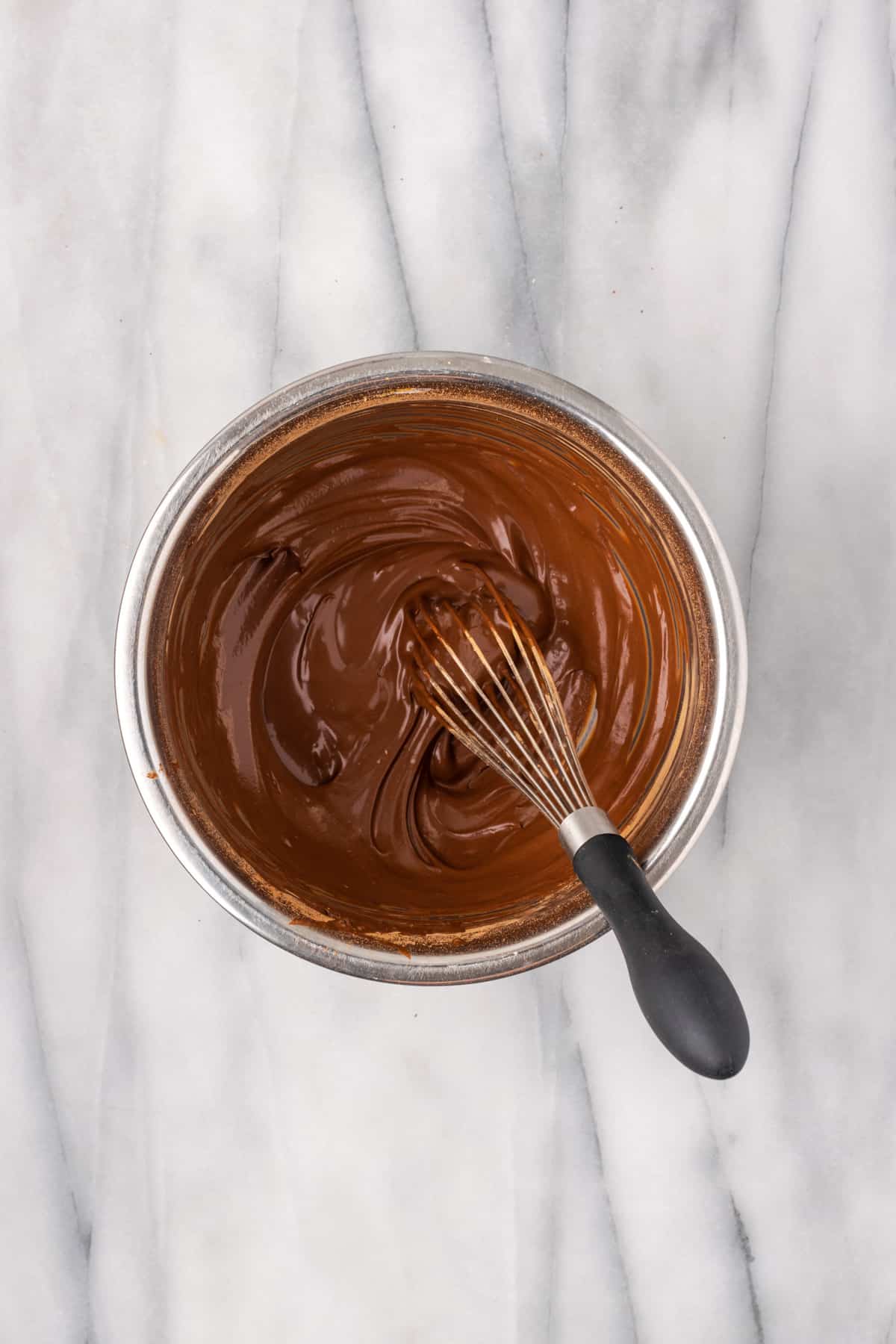 Chocolate sauce mixed in a metal bowl.