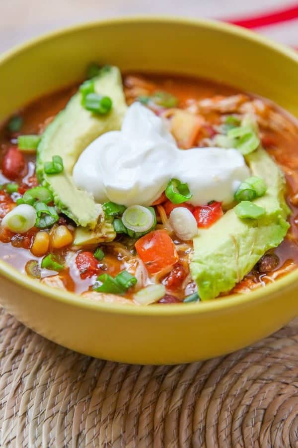 A closeup of taco soup garnished with sour cream and avocado slices.