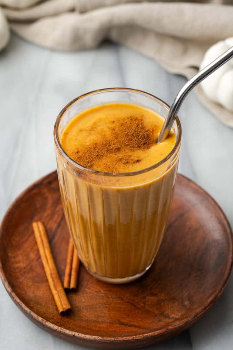 A pumpkin spice smoothie served in a tall glass and garnished with a sprinkle of cinnamon.