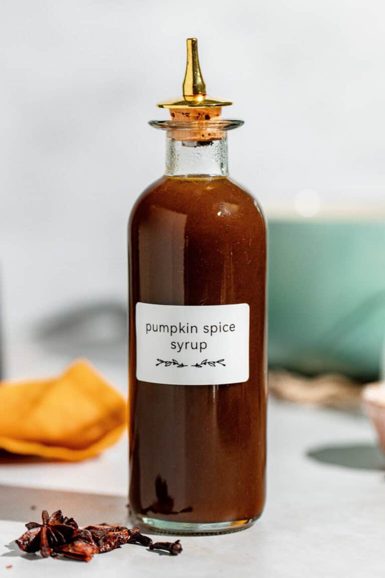A small bottle of homemade pumpkin spice syrup sitting on a counter.