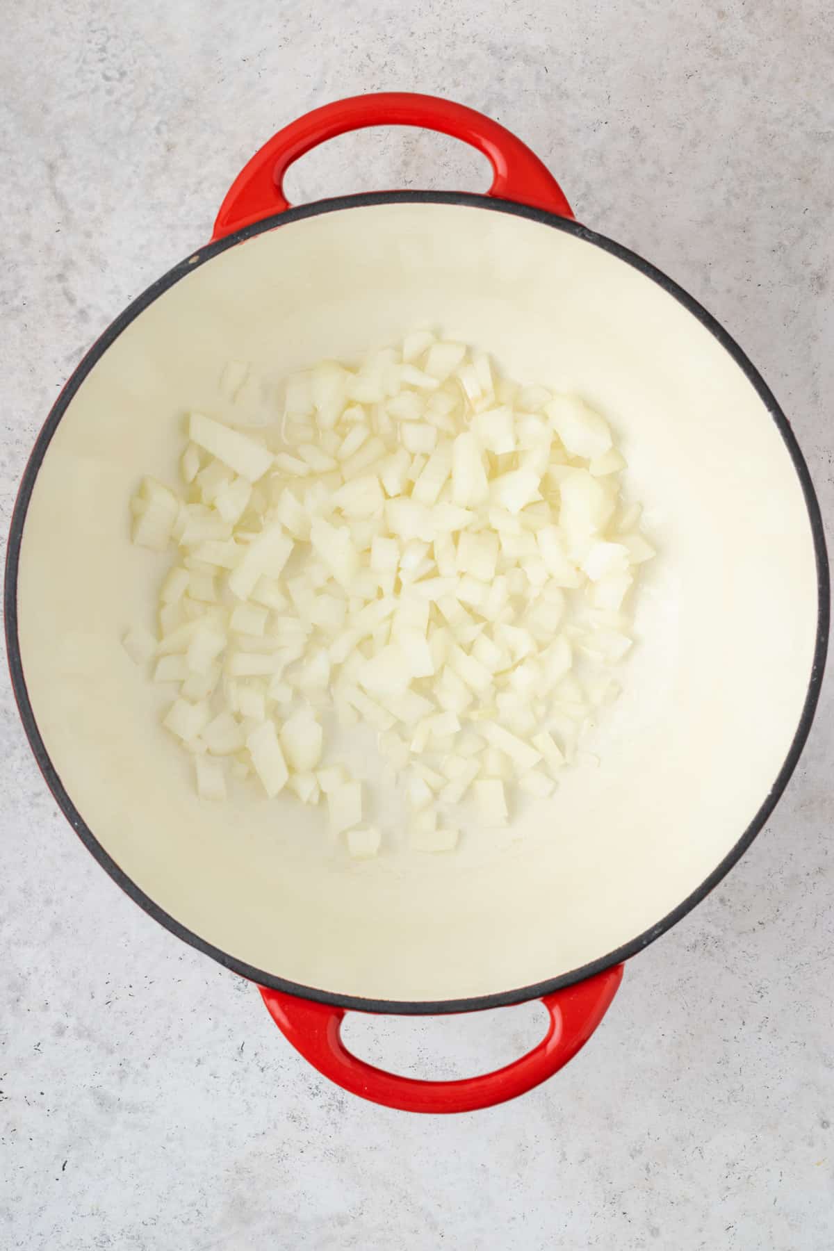 Onions cooking in olive oil in a dutch oven pot.