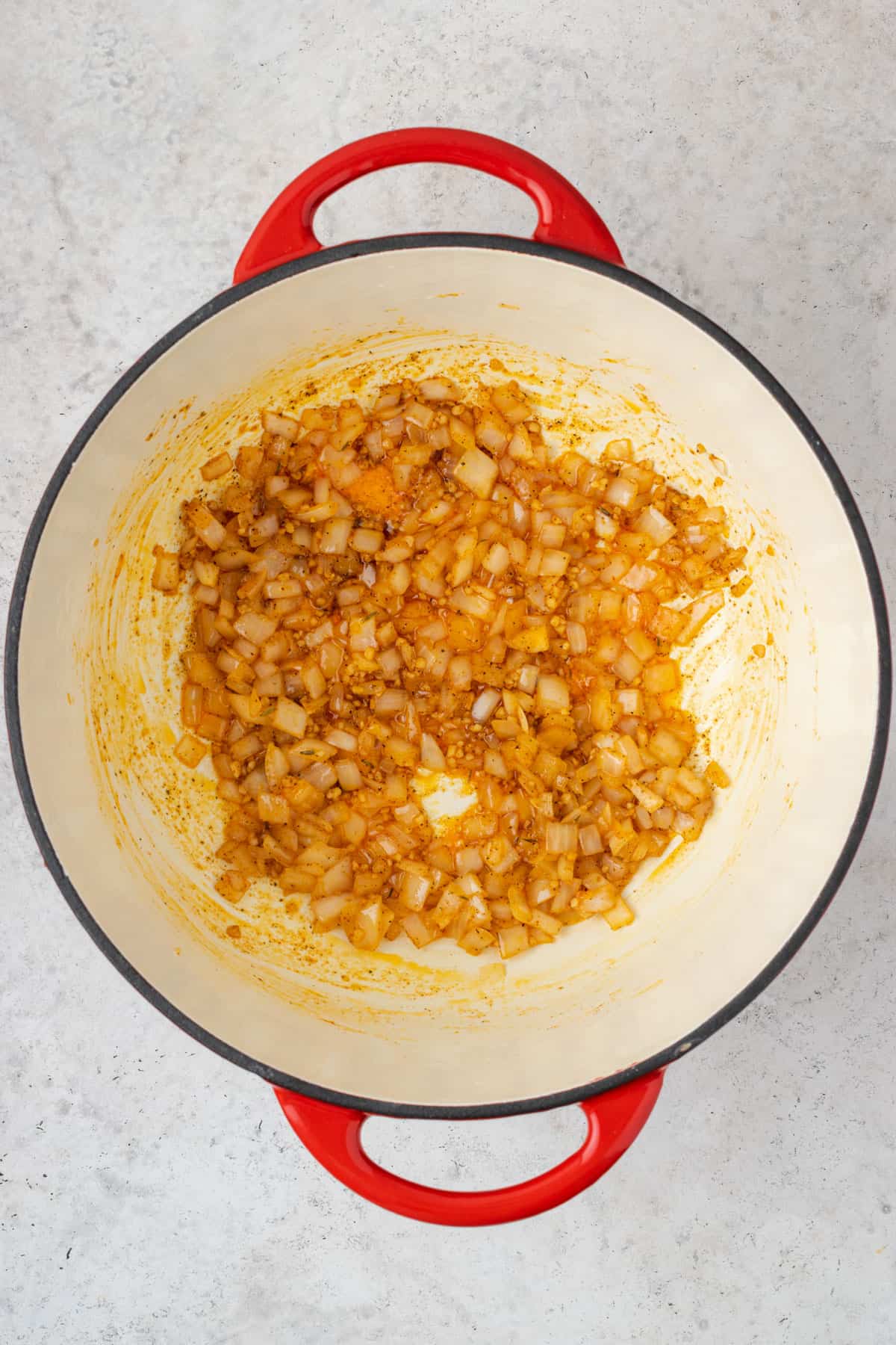 Onions mixed with spices and garlic in a dutch oven pot.