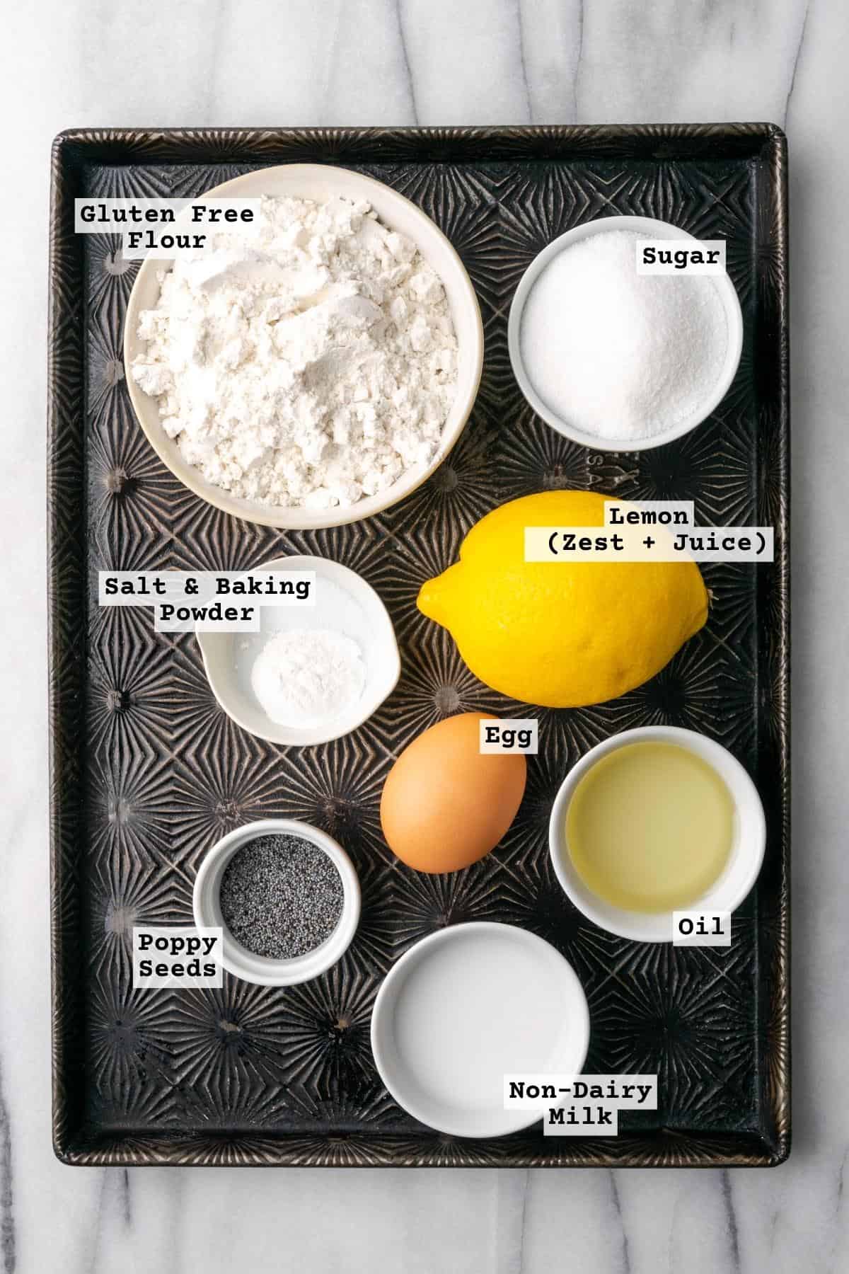 Ingredients for gluten free lemon poppy seed muffins on a metal baking sheet.