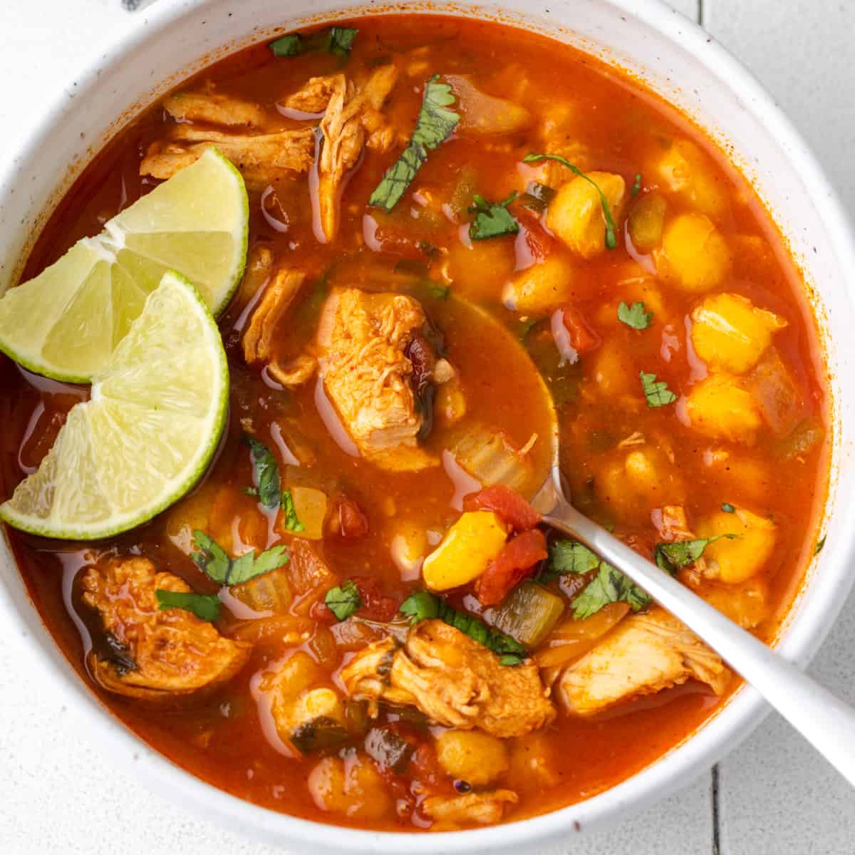 A bowl of chilis southwest chicken soup topped with cilantro and lime slices.