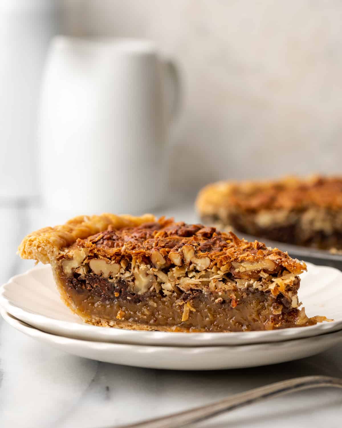 A slice of german chocolate pecan pie on a white plate.