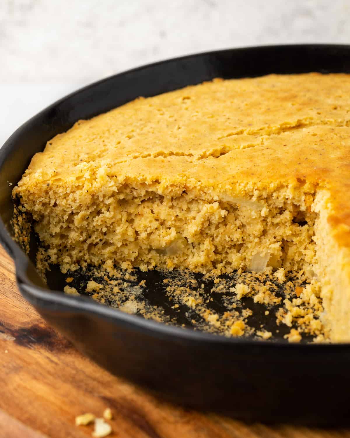 A sliced batch of cornbread in a cast iron skillet.