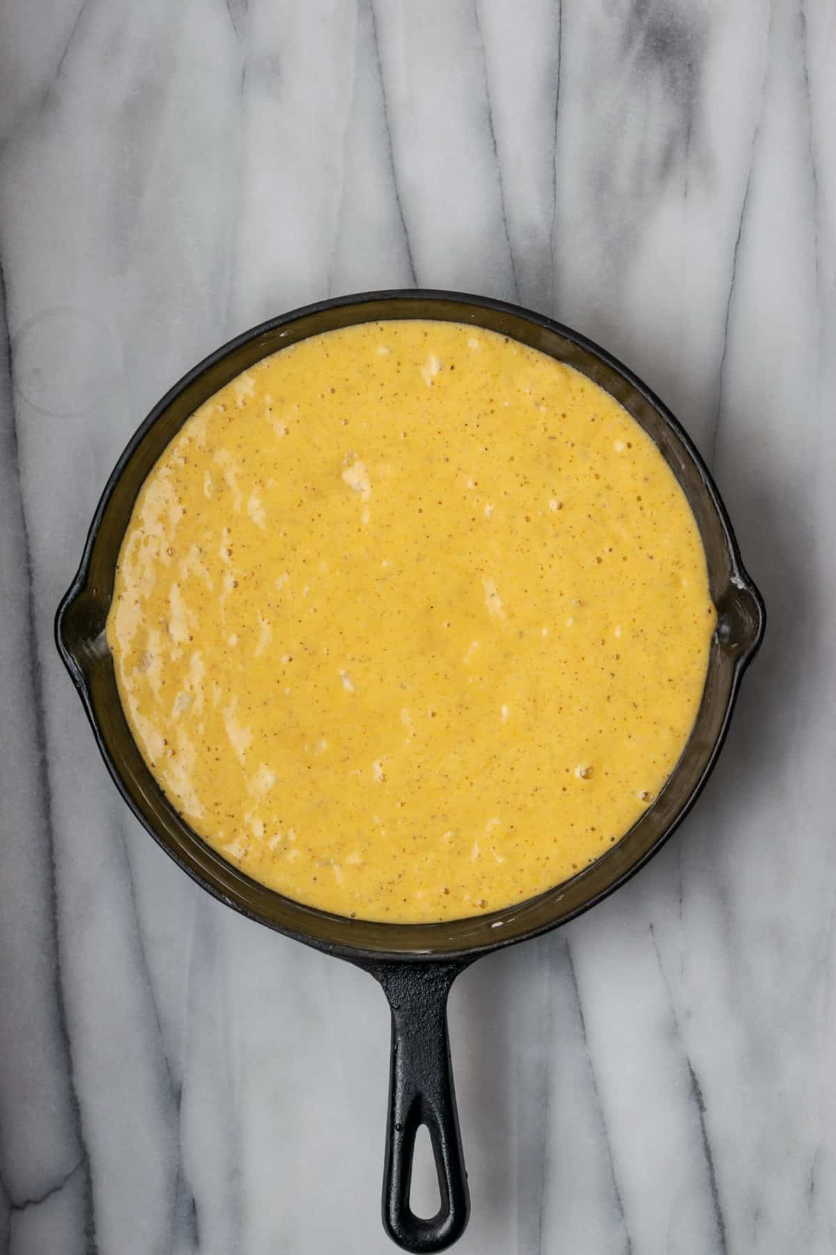 Unbaked cornbread batter in a cast iron skillet.
