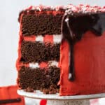 A chocolate peppermint cake coated in red frosting and covered with a chocolate drip.
