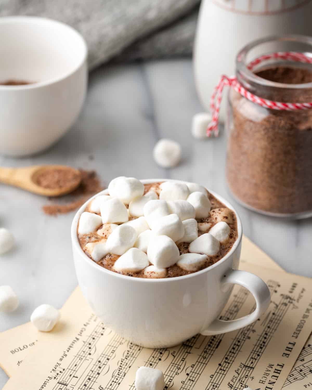 Hot chocolate with marshmallows beside a jar of dairy free hot chocolate mix. 