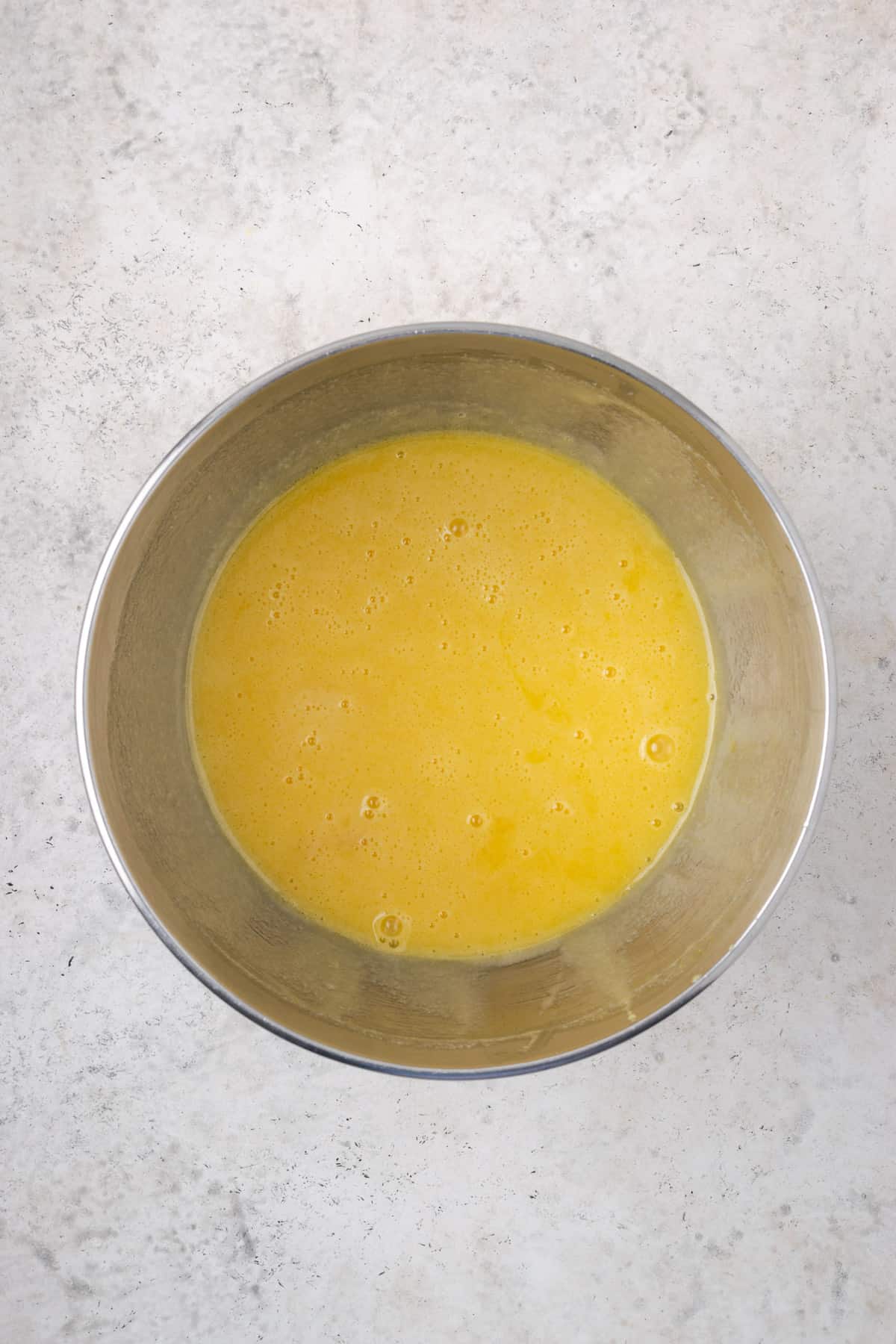 Partially mixed cake batter in a large metal mixing bowl.