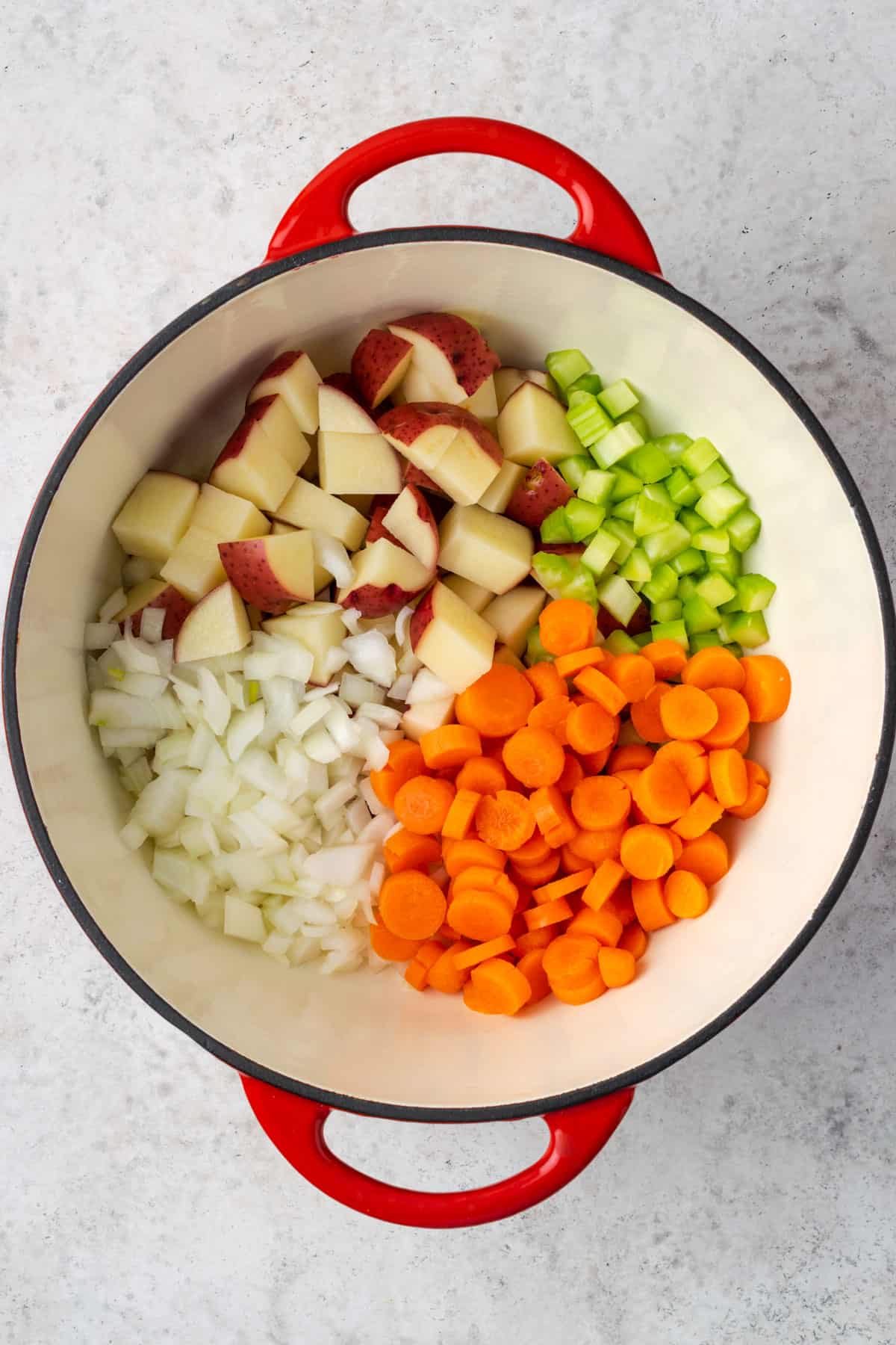 A large pot with potatoes, celery, onions and carrots.