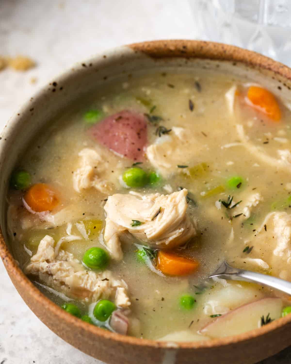 Closeup of a spoon dipping into a bowl of chicken pot pie soup.