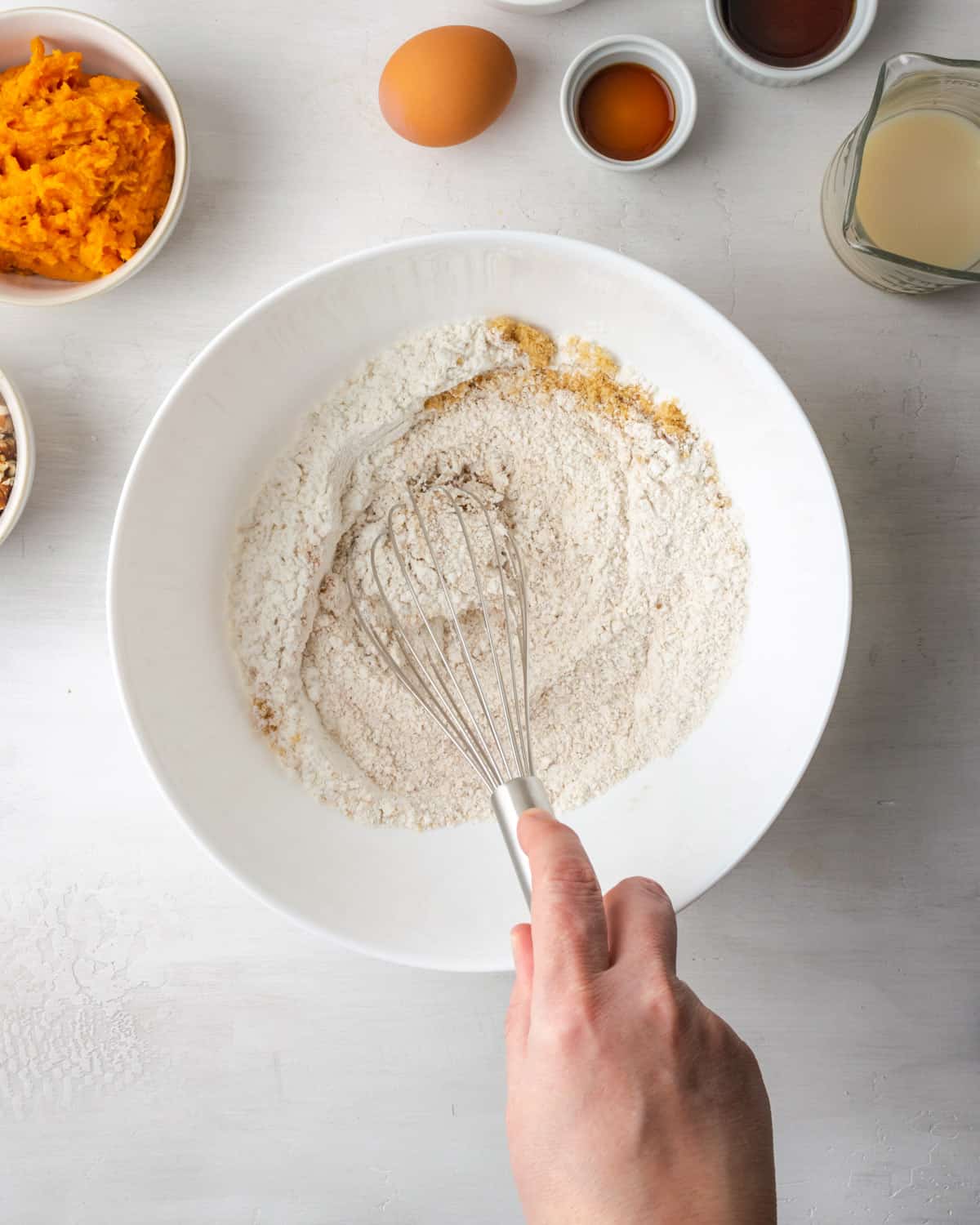 A hand whisking dry ingredients together.