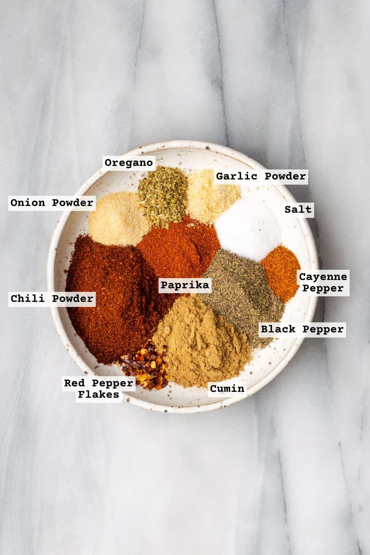 Ingredients for homemade taco seasoning all spread out on a white plate.