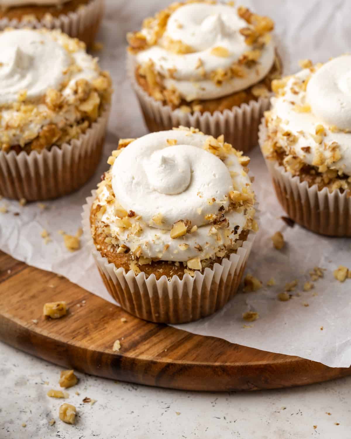 Gluten free carrot cake cupcakes decorated with cream cheese frosting and chopped walnuts.