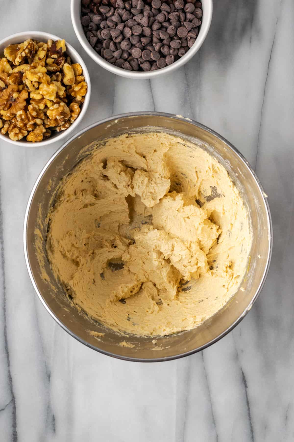 Partially mixed levain cookie dough in a large metal bowl.