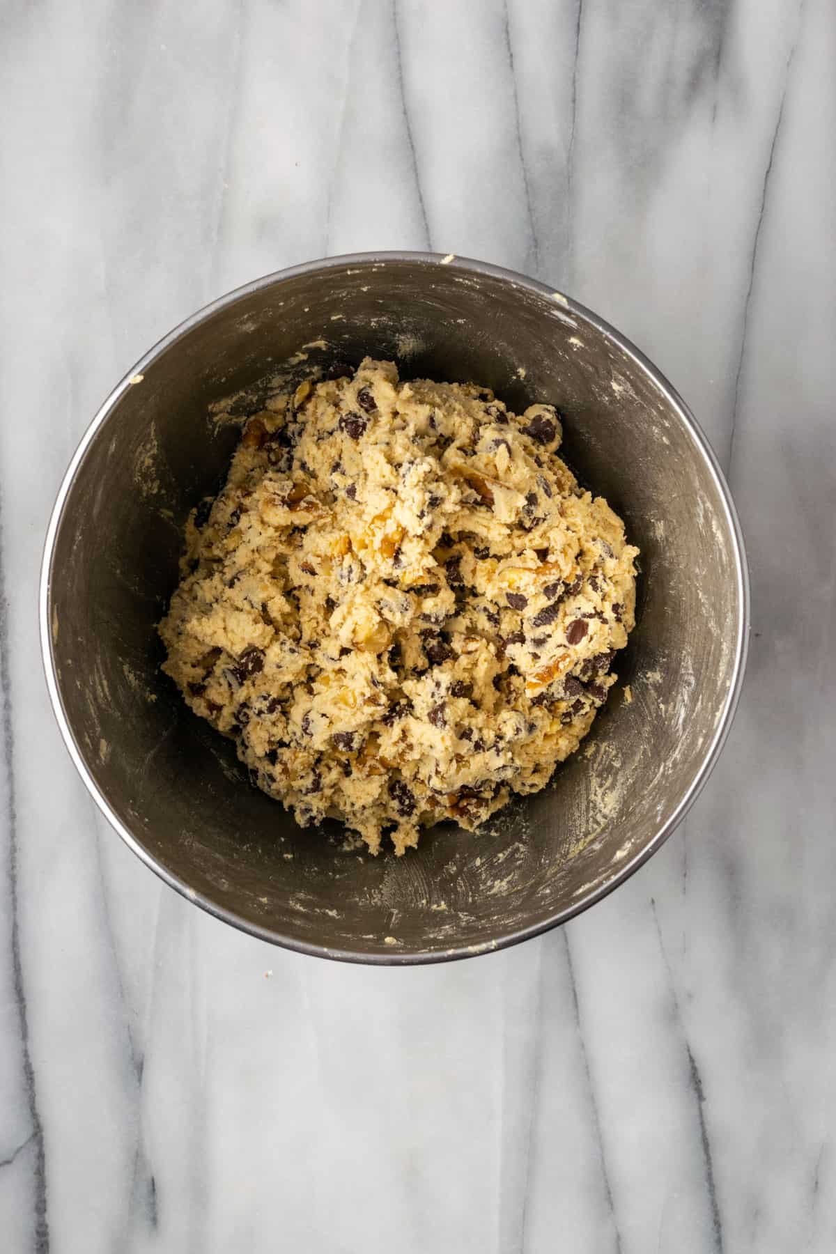 Unbaked levain chocolate chip cookie dough in a large metal bowl.