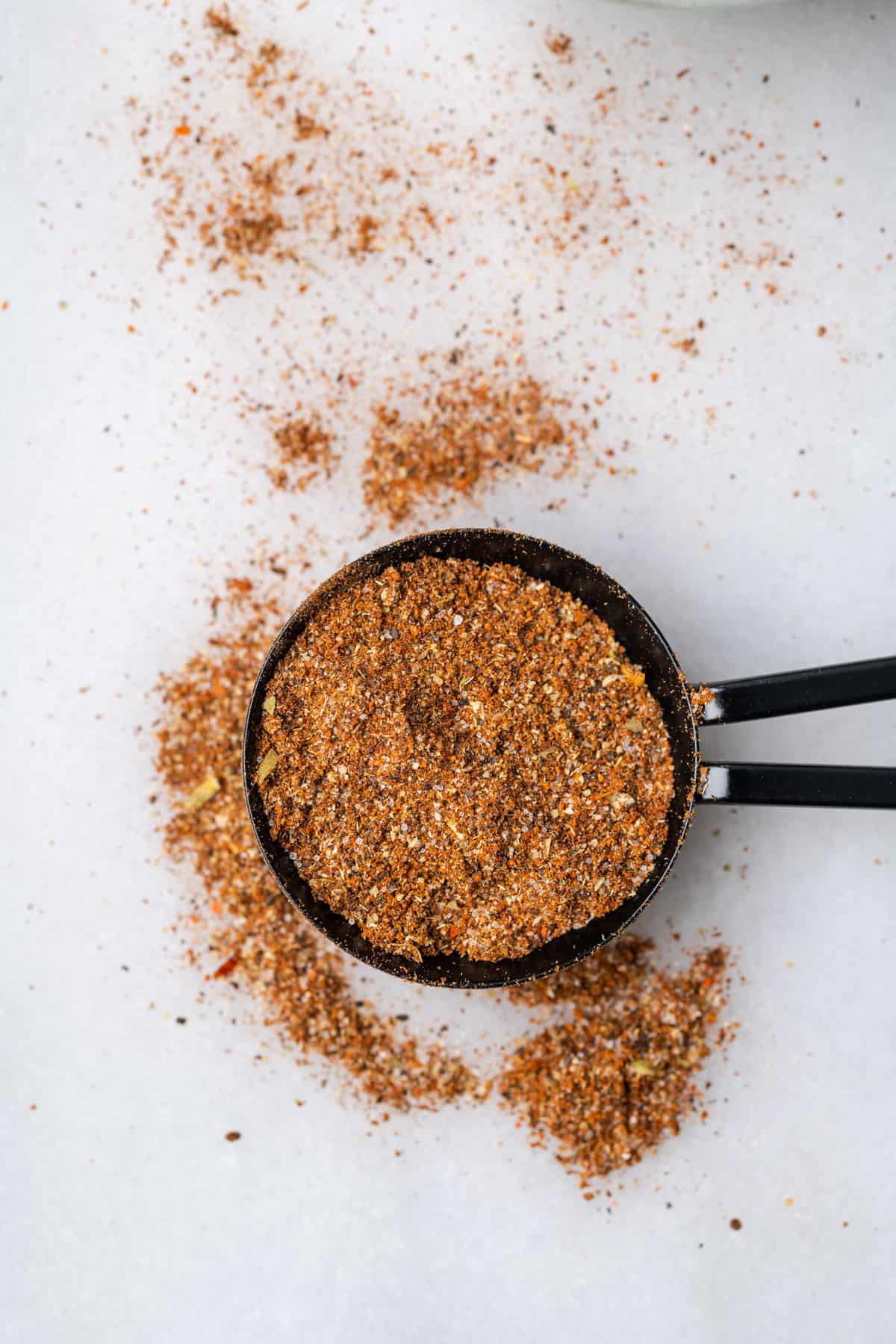 A tablespoon of taco seasoning spilled on a white table.