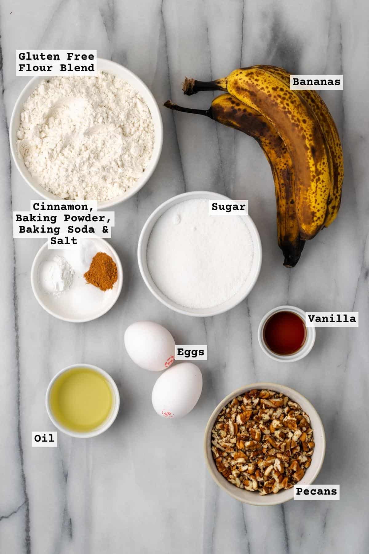 Ingredients for banana bread with pecans on a white marble table.