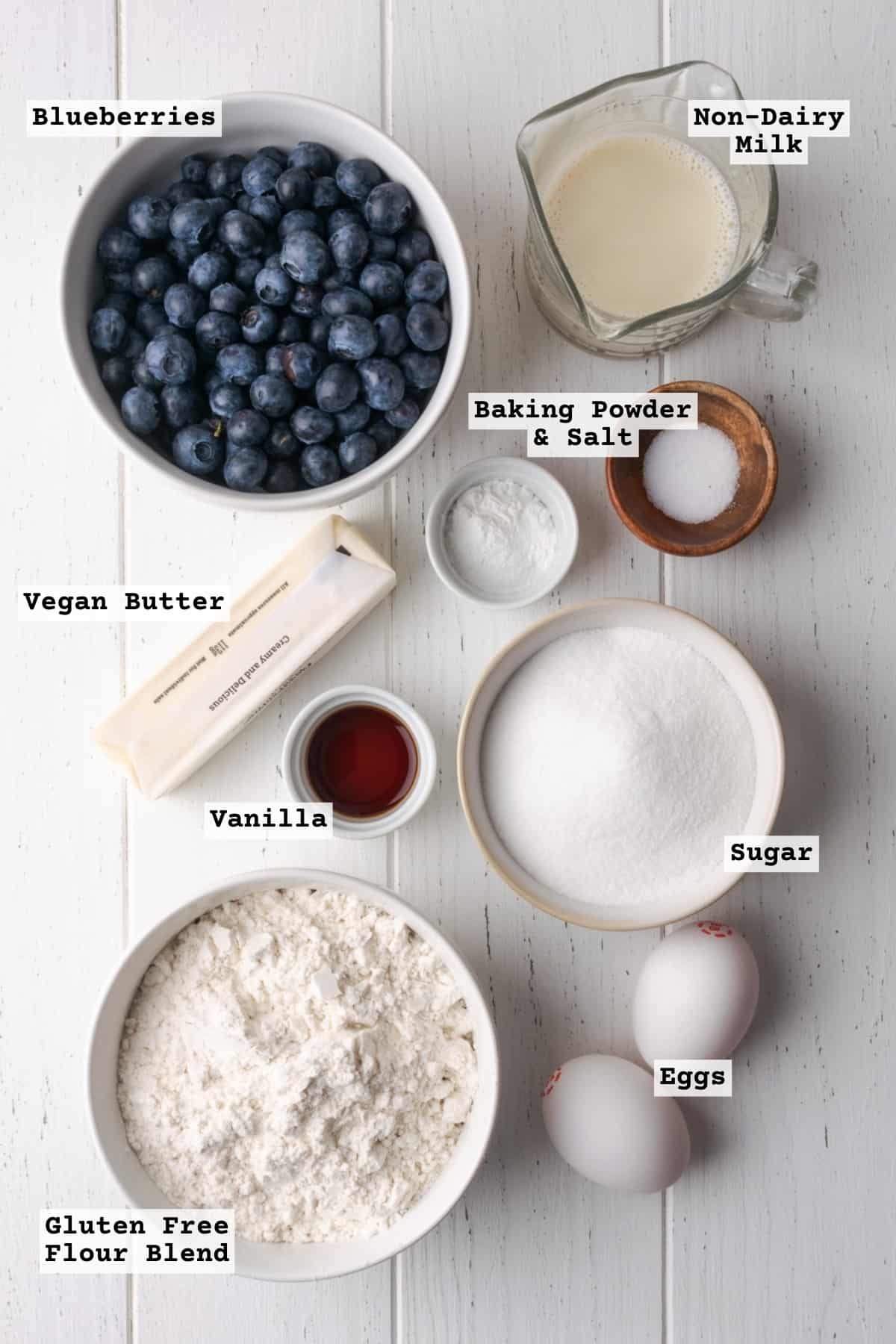 Ingredients for gluten free blueberry cake on a white wooden table.