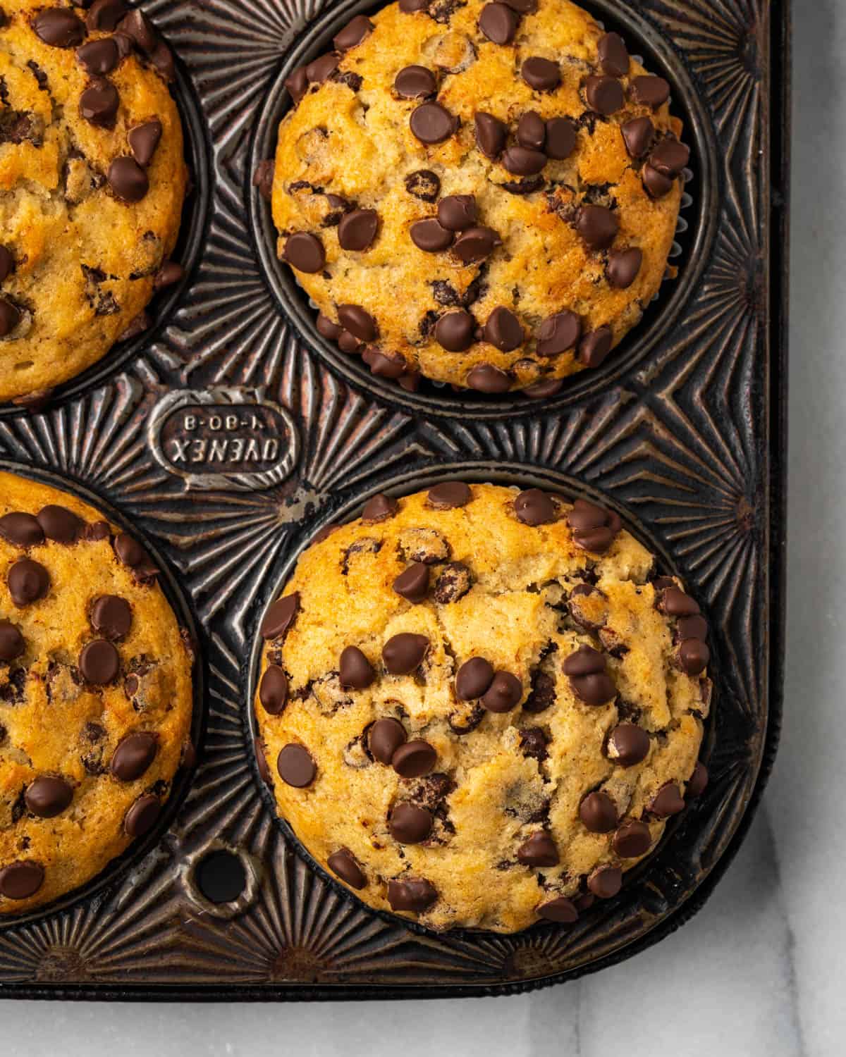 A muffin tin with baked banana chocolate chip muffins.