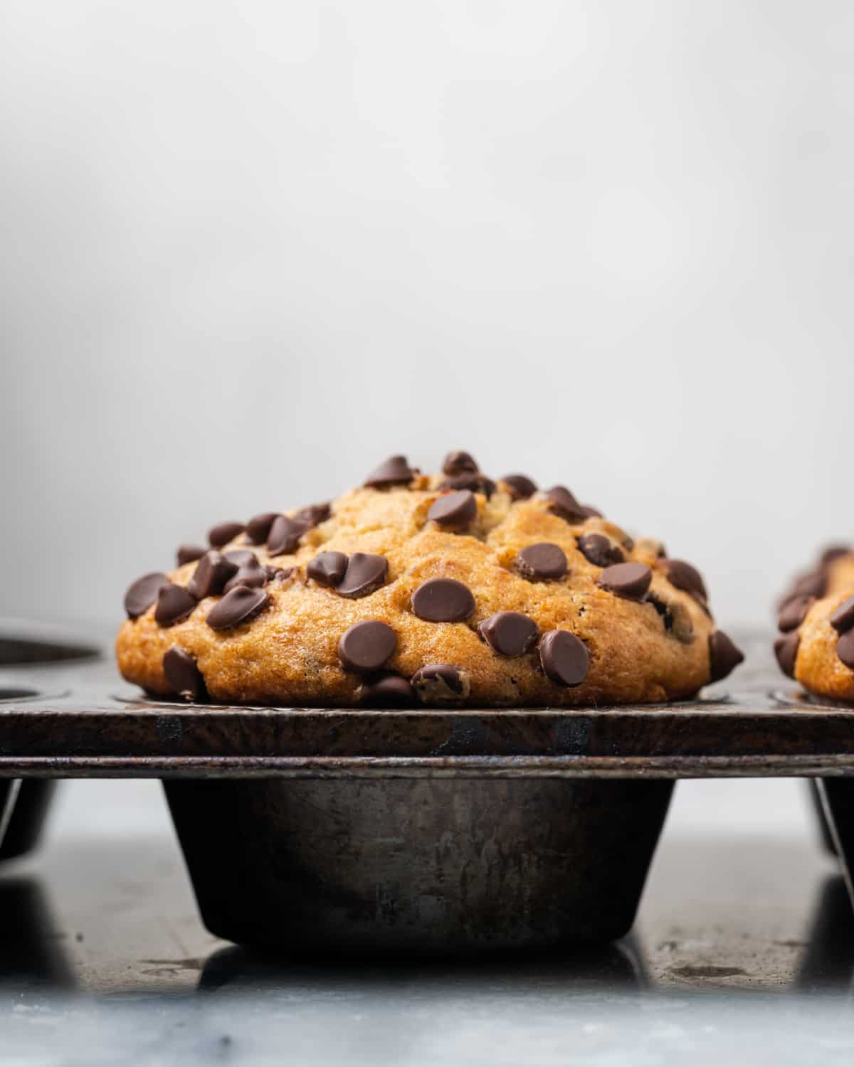 A banana chocolate chip muffin sitting in a muffin pan.