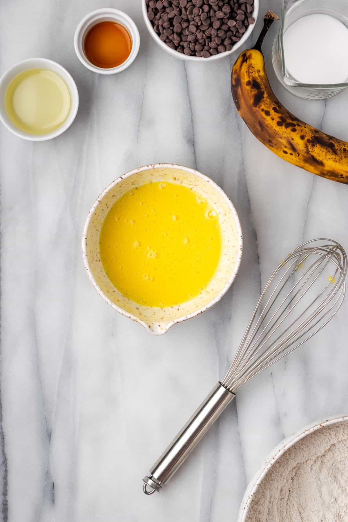 An egg that has been whisked until bubbly in a small white bowl.