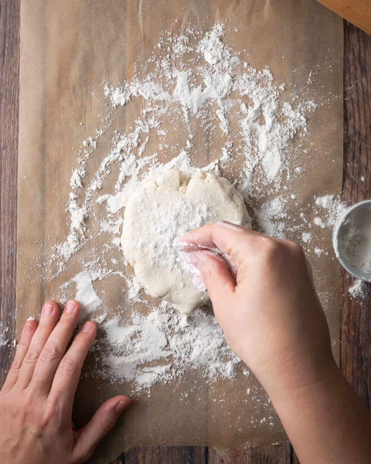 A disc of pie dough on a floured piece of parchment paper.