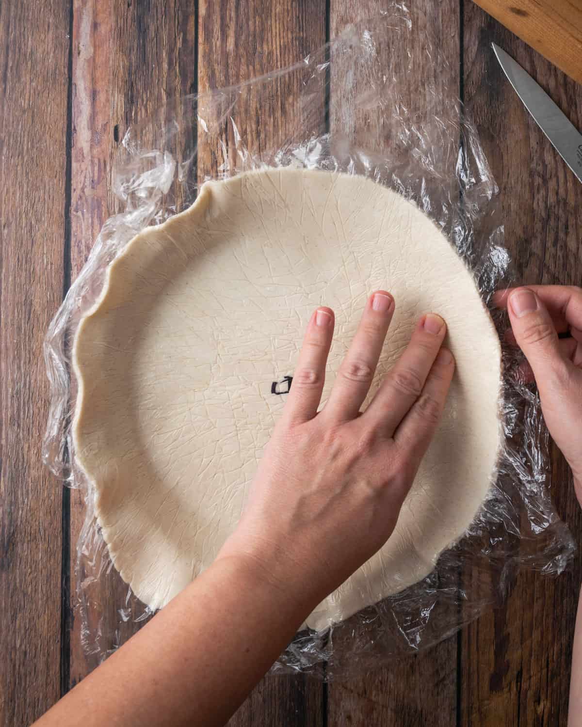 Pie dough being shaped into a pie tin.