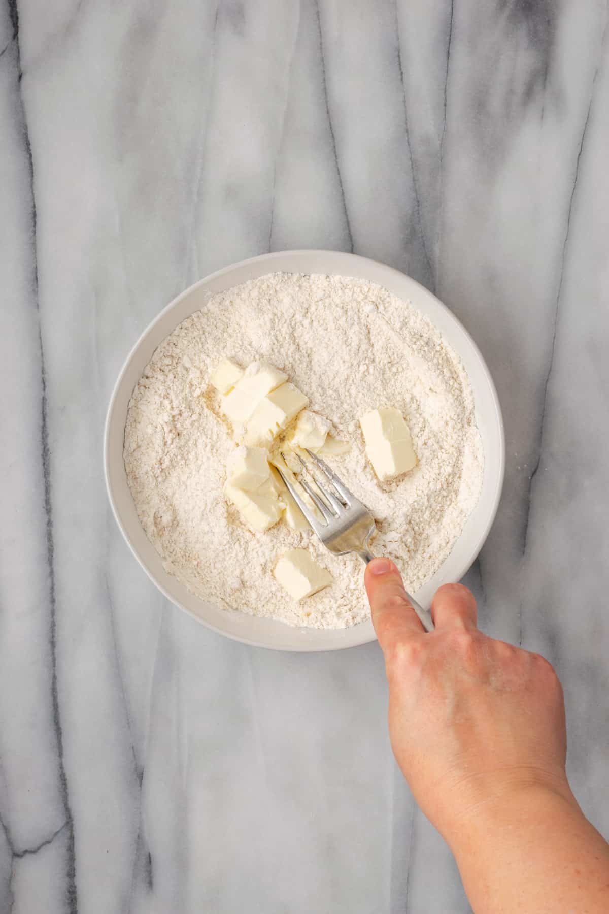 Butter being smashed into the dry ingredients with a fork.