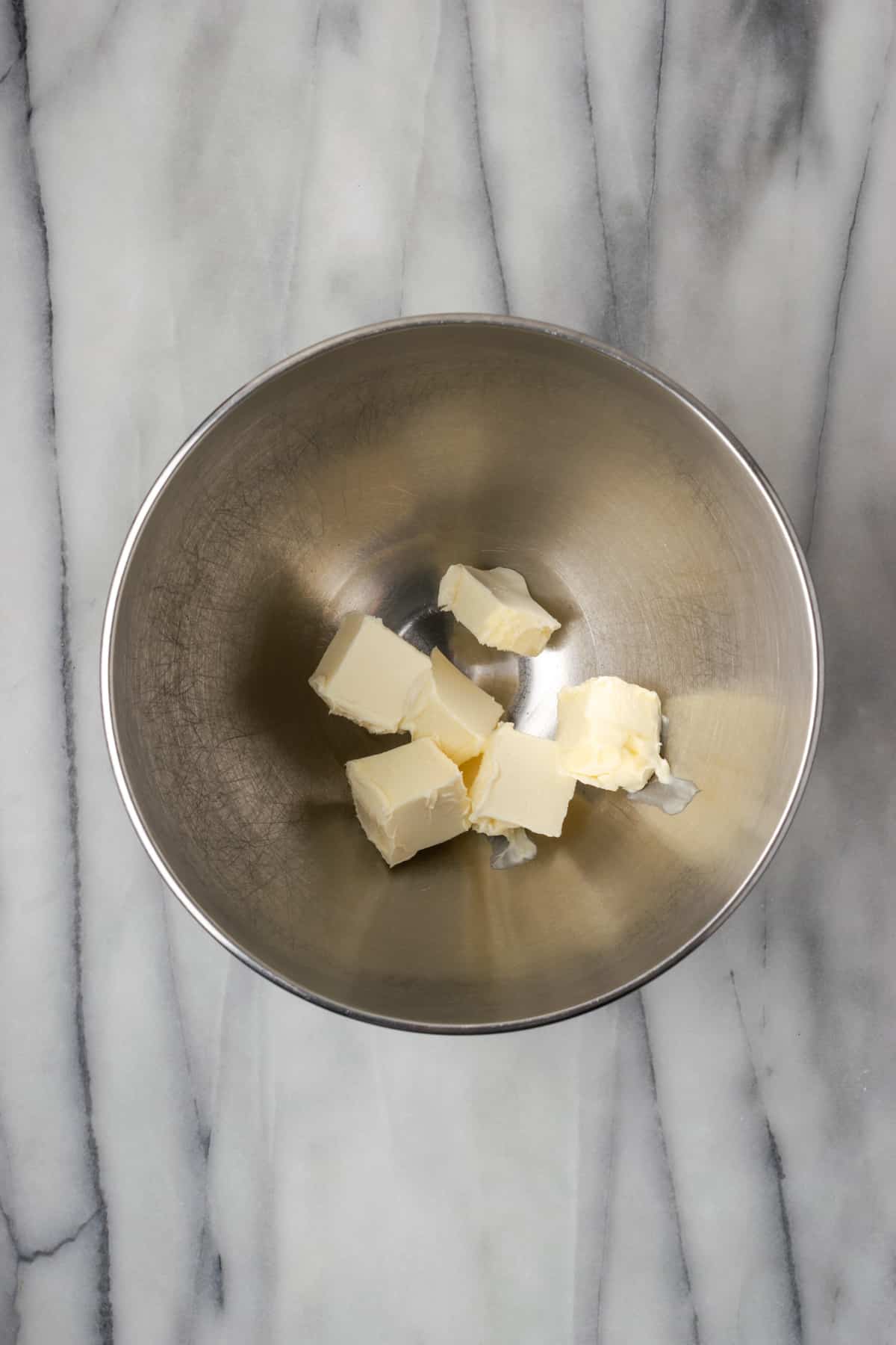 Slices of butter in a large metal mixing bowl.