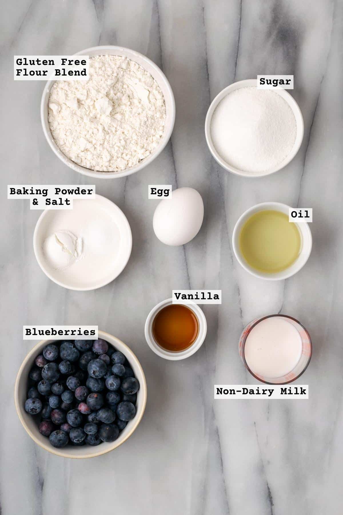 Ingredients for gluten free blueberry muffins on a white marble table.