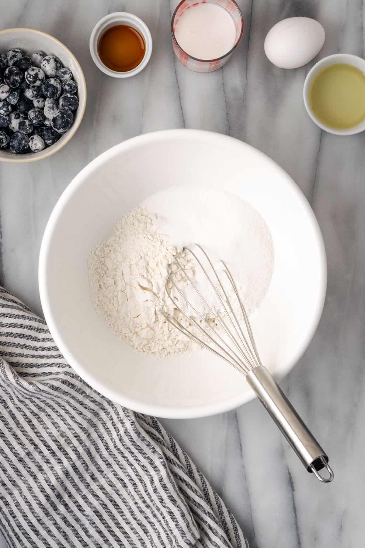 Gluten free flour, sugar, baking powder and salt combined together in a large white mixing bowl.