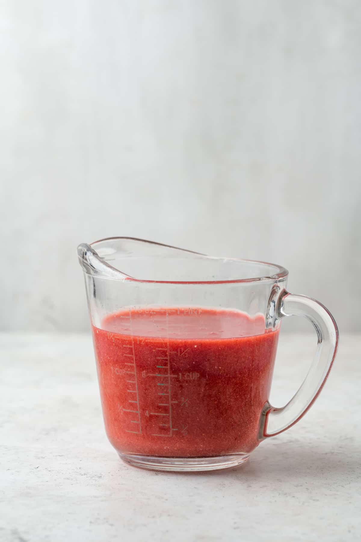 A glass measuring cup showing about 1 ½ cups of strawberry puree. 