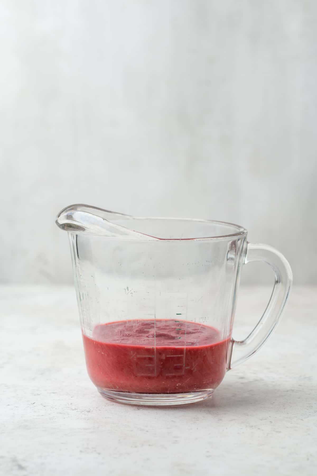 Reduced strawberry puree in a glass measuring cup. 