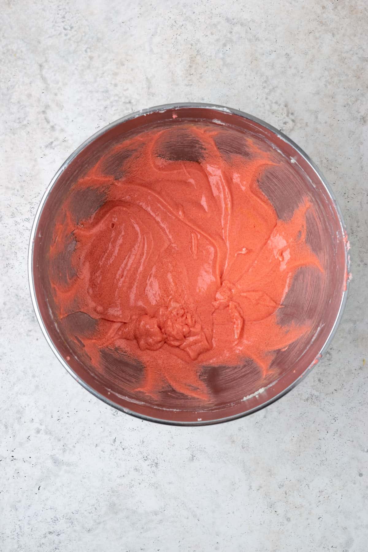 Partially mixed cake batter in a large metal mixing bowl.