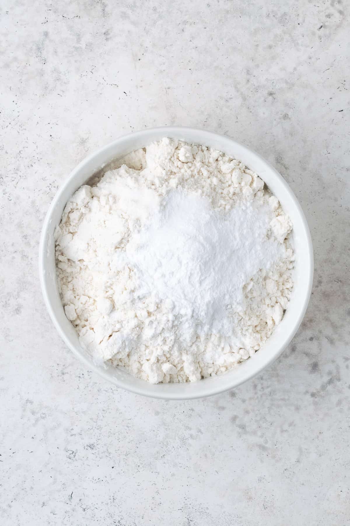 Gluten free flour, baking powder and salt combined in a small white bowl.