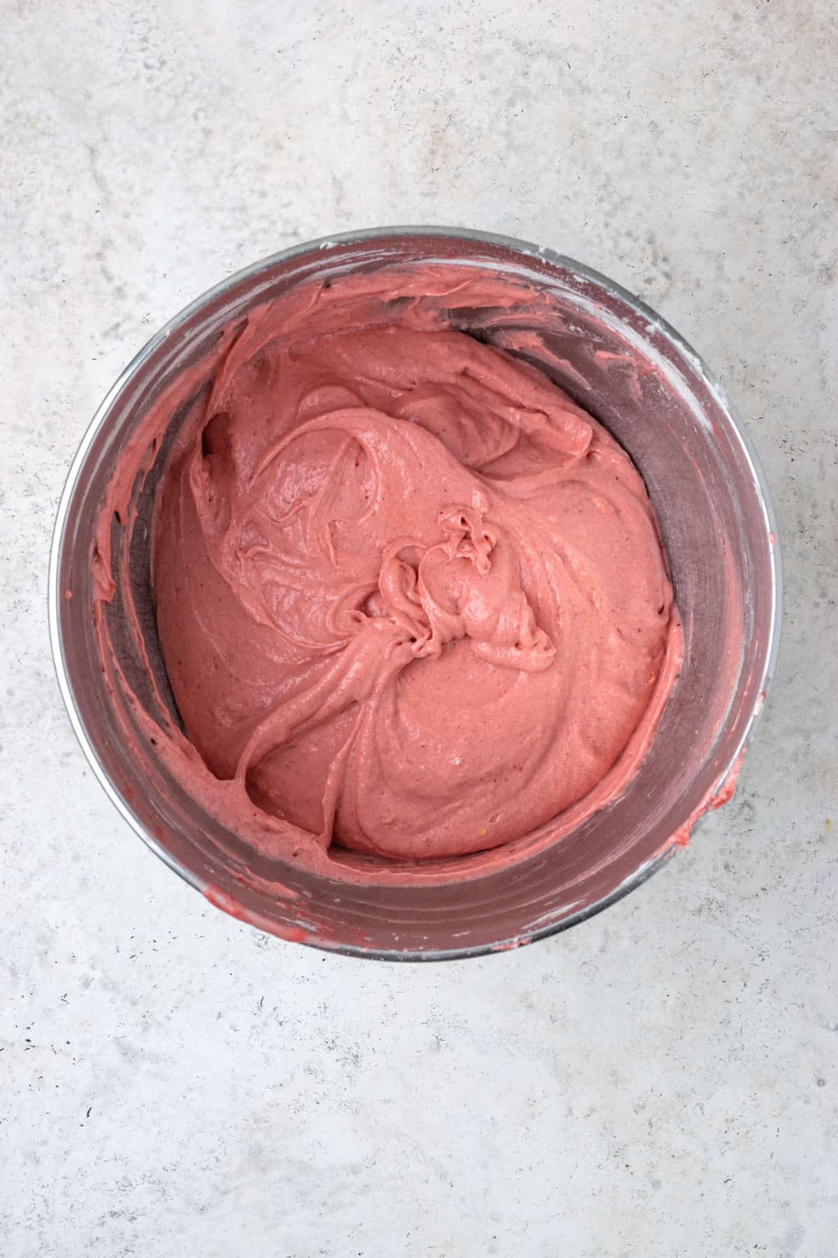 Strawberry cake batter in a large metal mixing bowl.