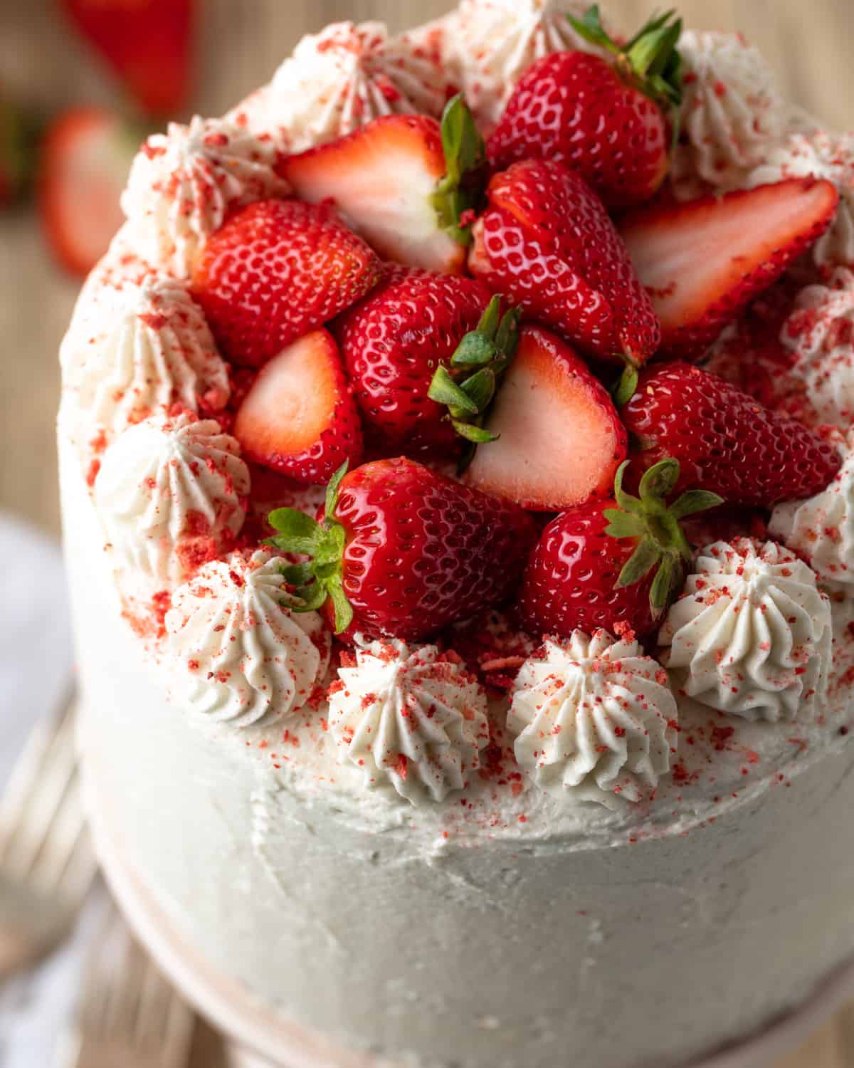 A gluten free strawberry cake topped with cream cheese frosting and fresh strawberries.