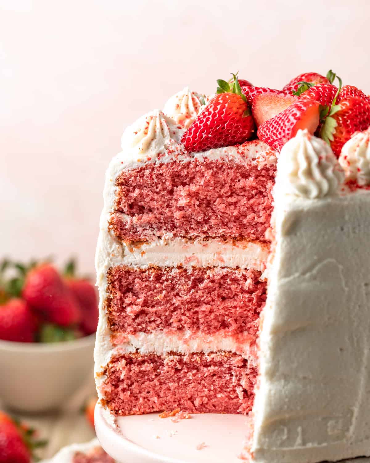 A gluten free strawberry cake with a slice taken out exposing the pink cake layers.