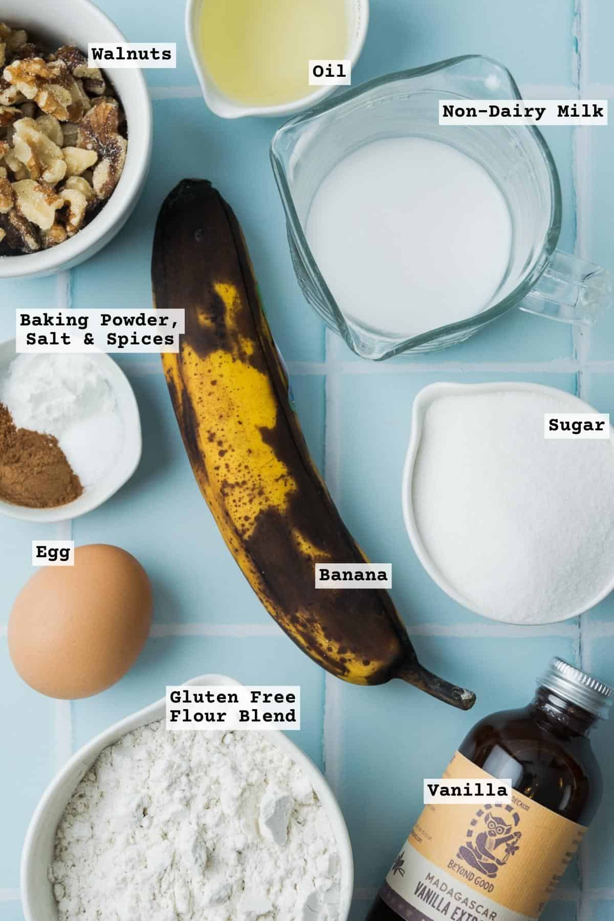 Ingredients for gluten free banana muffins on a blue tile table.