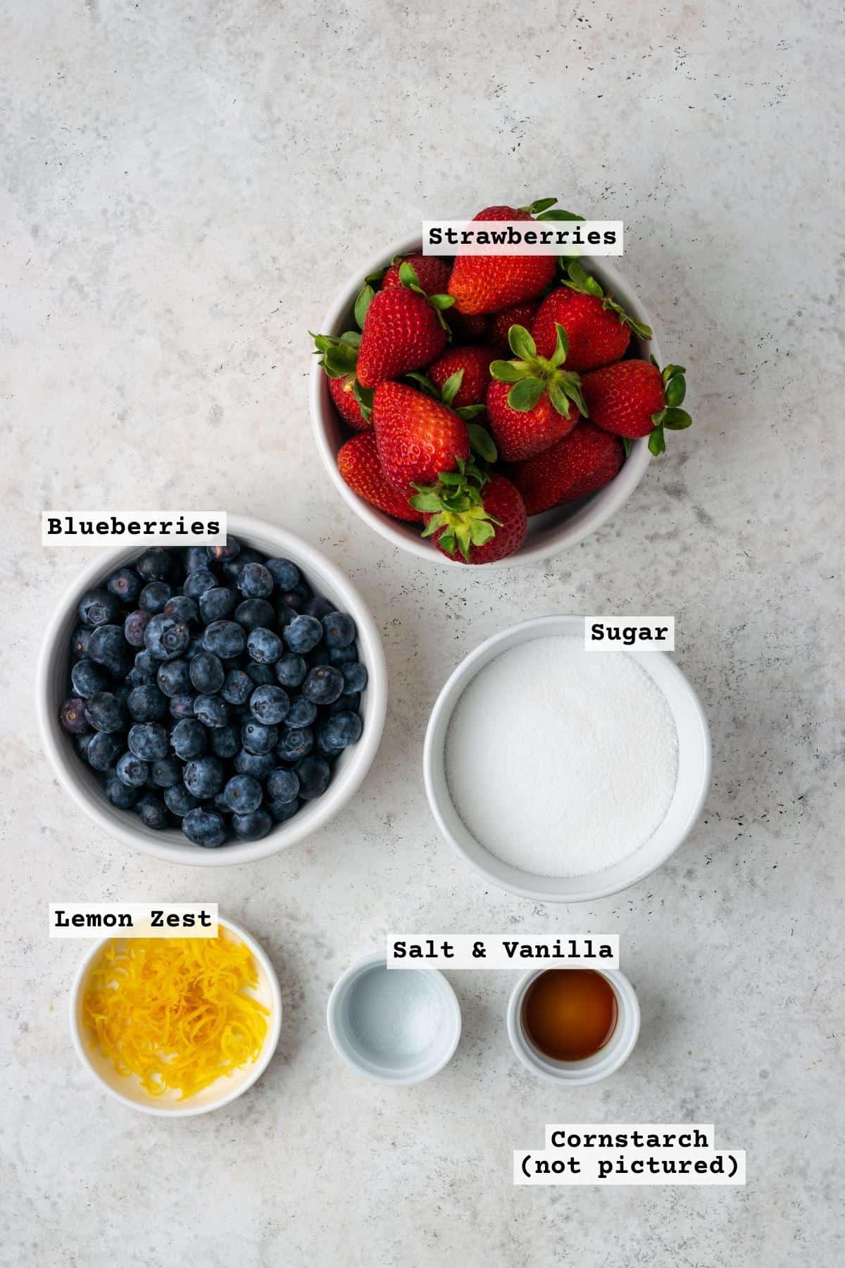 Ingredients for strawberry blueberry pie filing on a white table.