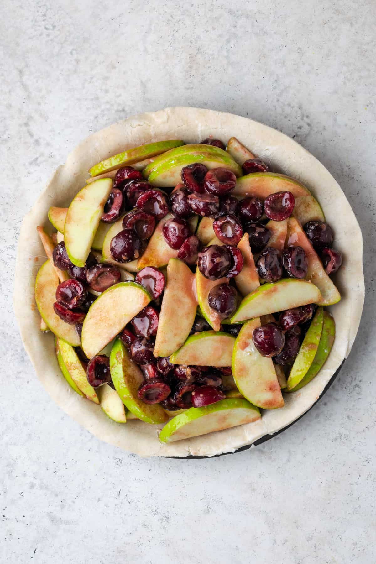 Apple cherry pie filling in an unbaked pie crust.