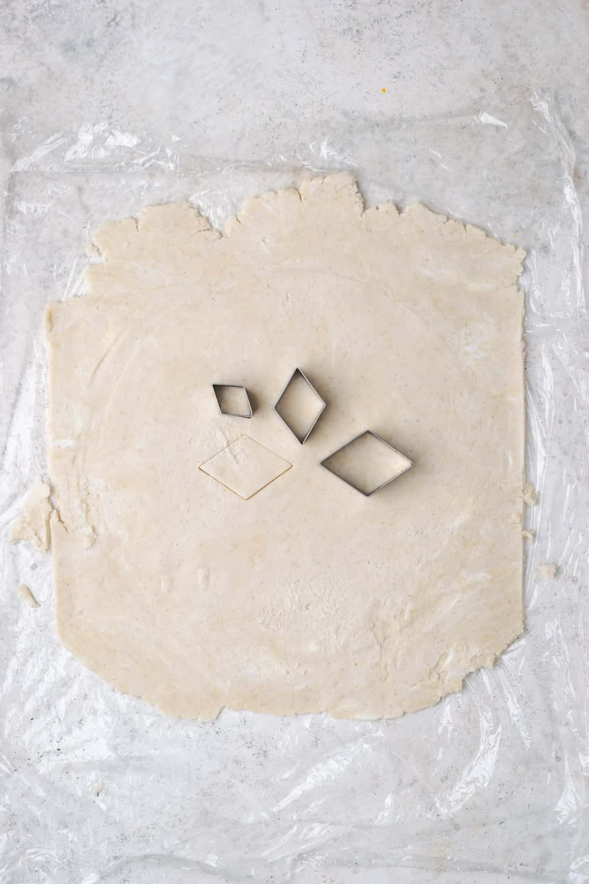 A sheet of pie dough with diamond shape holes cut out of the center. 