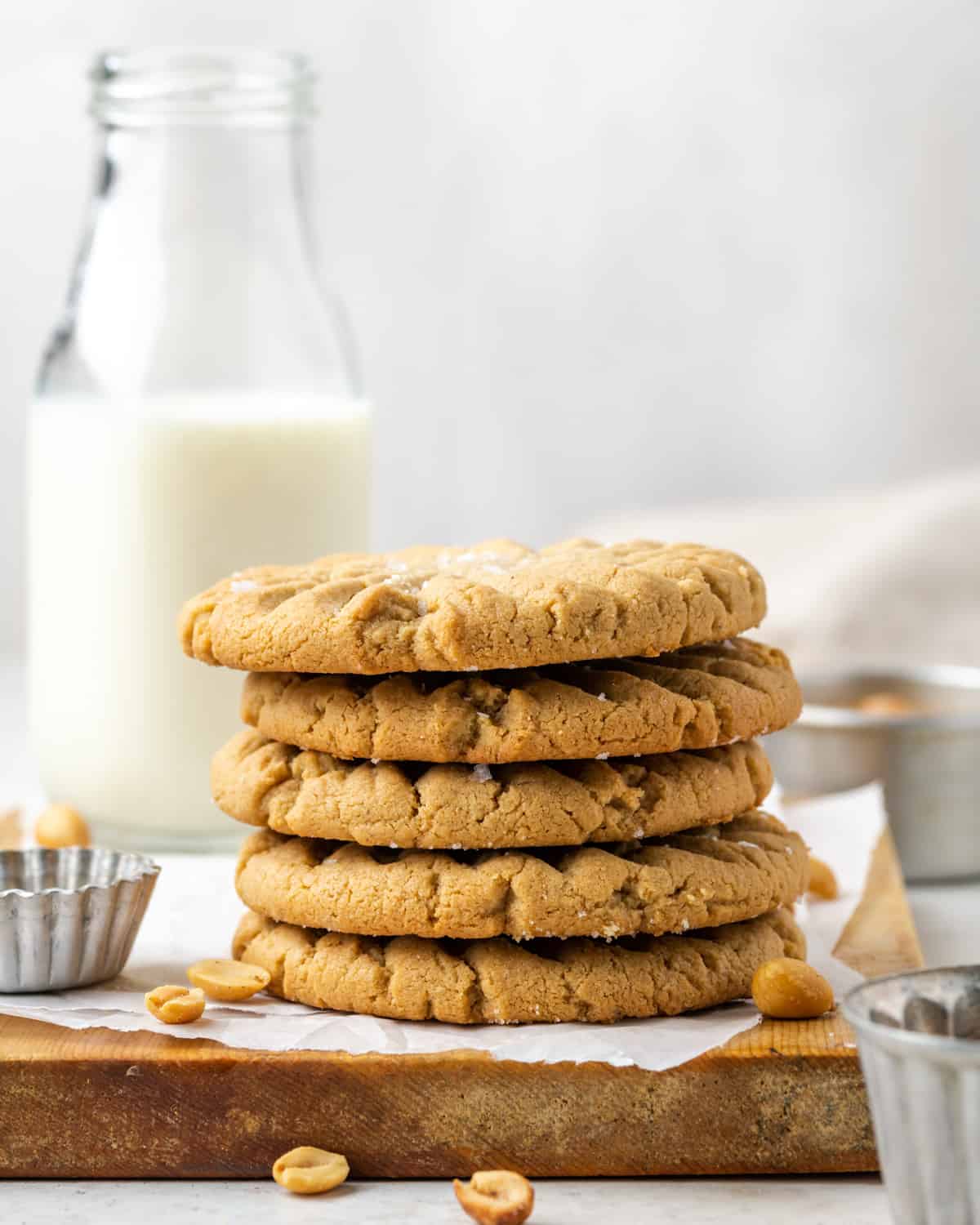 A stack of five gluten free peanut butter cookies sitting on a wooden cutting board.