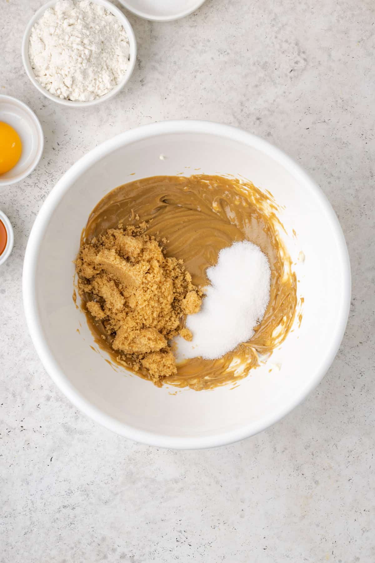 Sugar and brown sugar added to the peanut butter mixture in a large mixing bowl.