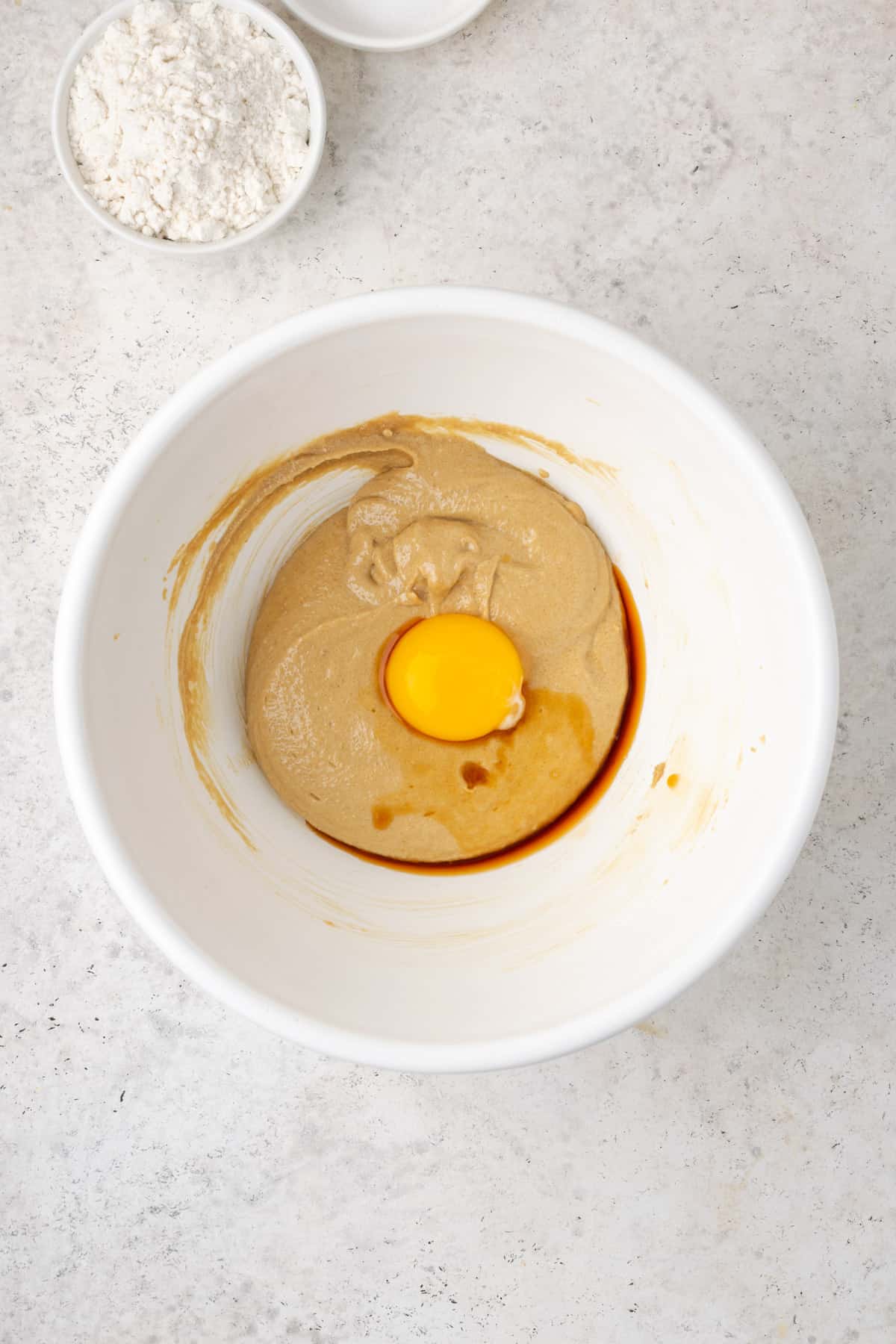 Egg yolk and vanilla extract added to the partially mixed peanut butter cookie dough.