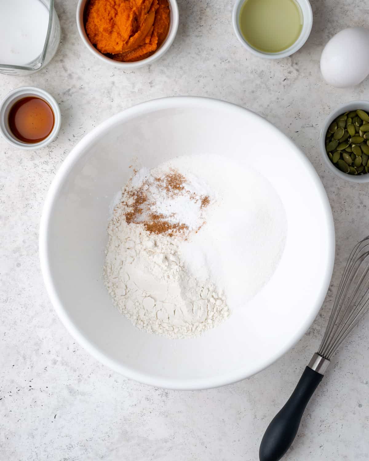 Gluten free flour, sugar, baking powder, salt and pumpkin spice mixed together in a large white bowl.