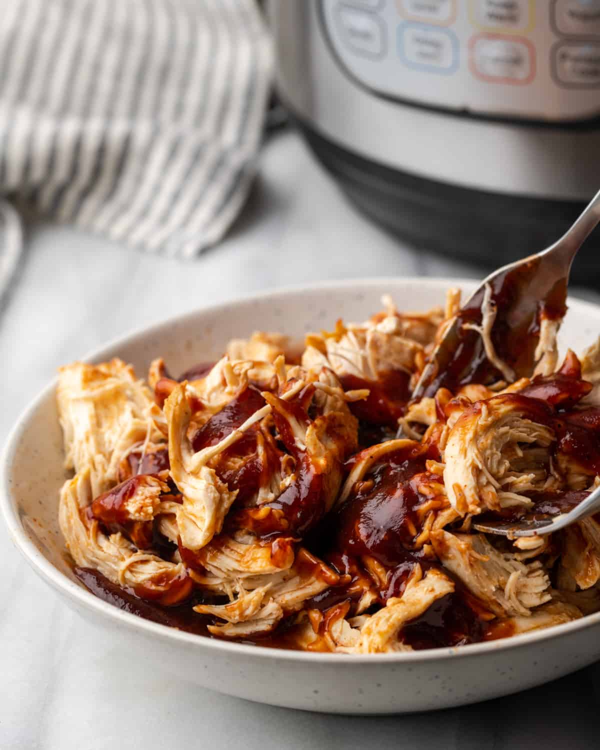 Shredded chicken being stirred with bbq sauce. 