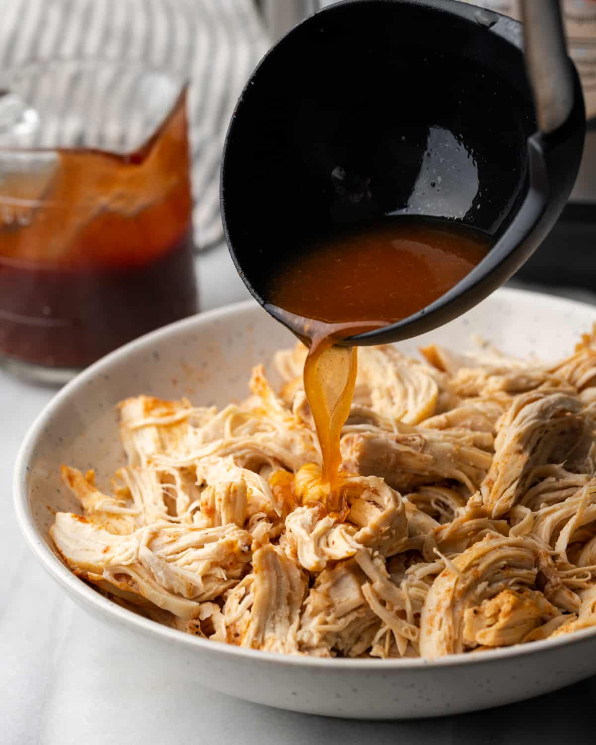 Broth being poured over pulled chicken. 